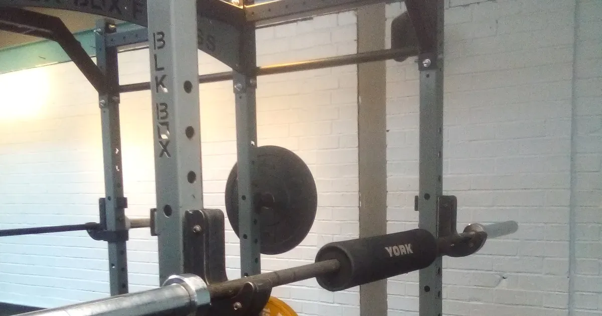 Barre chargée sur un rack de musculation, disques et fixations visibles