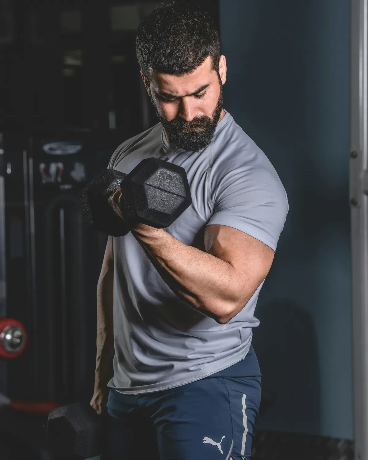 Pratiquant réalisant un curl biceps avec un haltère hexagonal, coude fixe le long du corps
