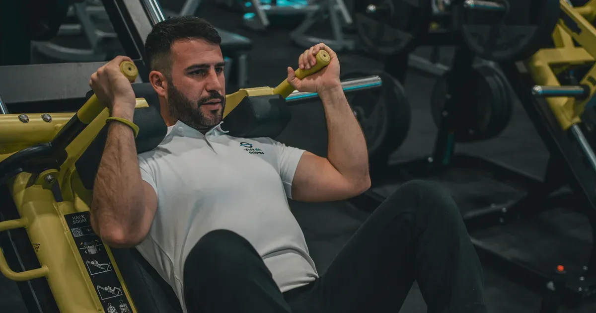 Pratiquant en position de hack squat sur une machine inclinée