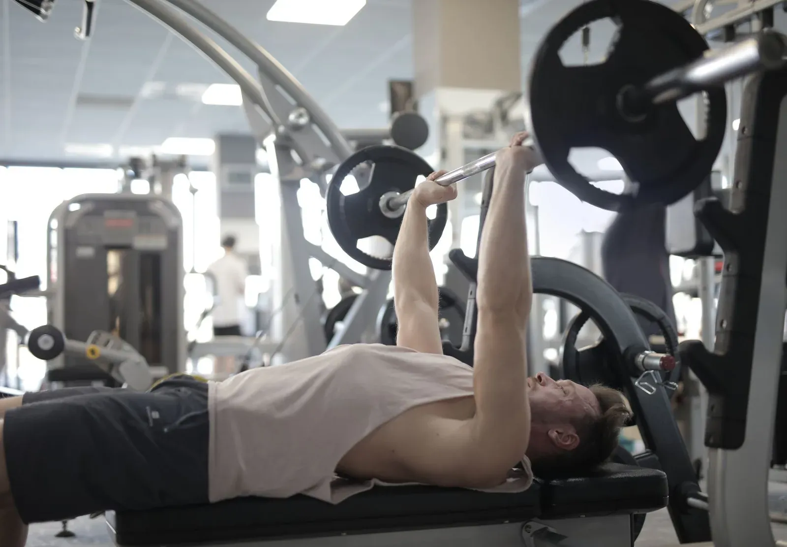 Pratiquant exécutant un développé couché à la barre dans une salle de musculation