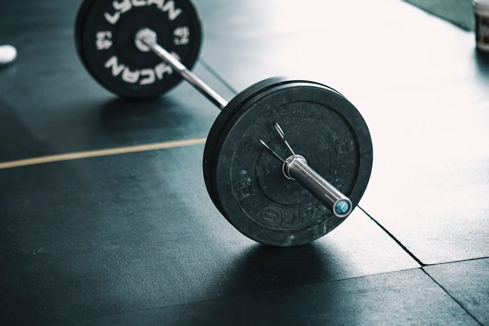 Gros plan sur une barre de musculation chargée de disques en fonte, posée au sol