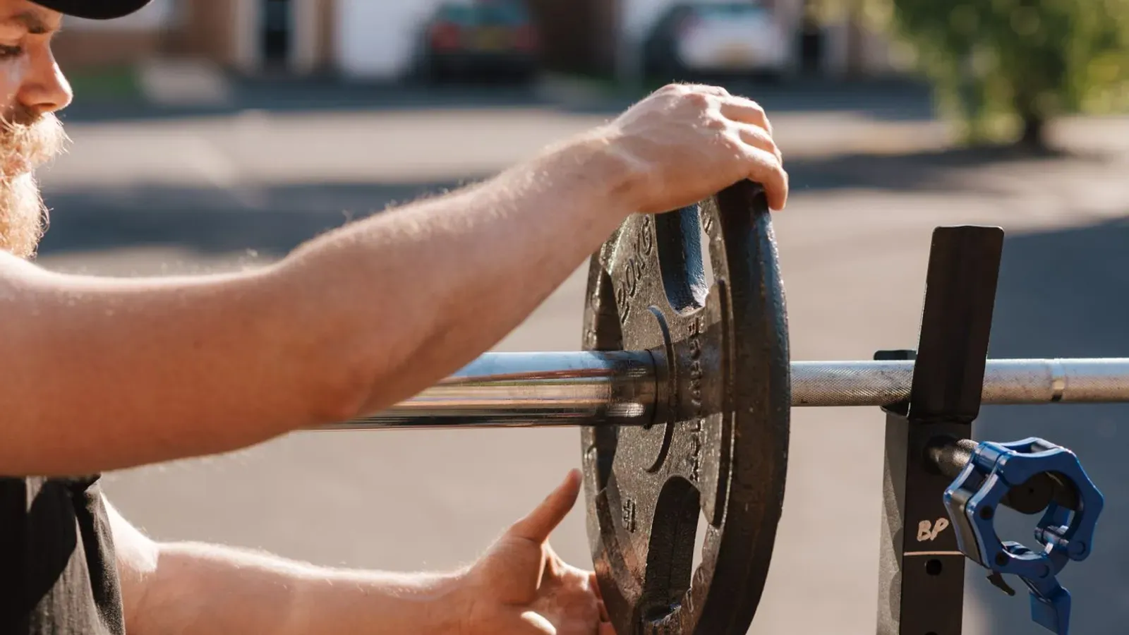 Pratiquant ajoutant un disque sur une barre de musculation chargée