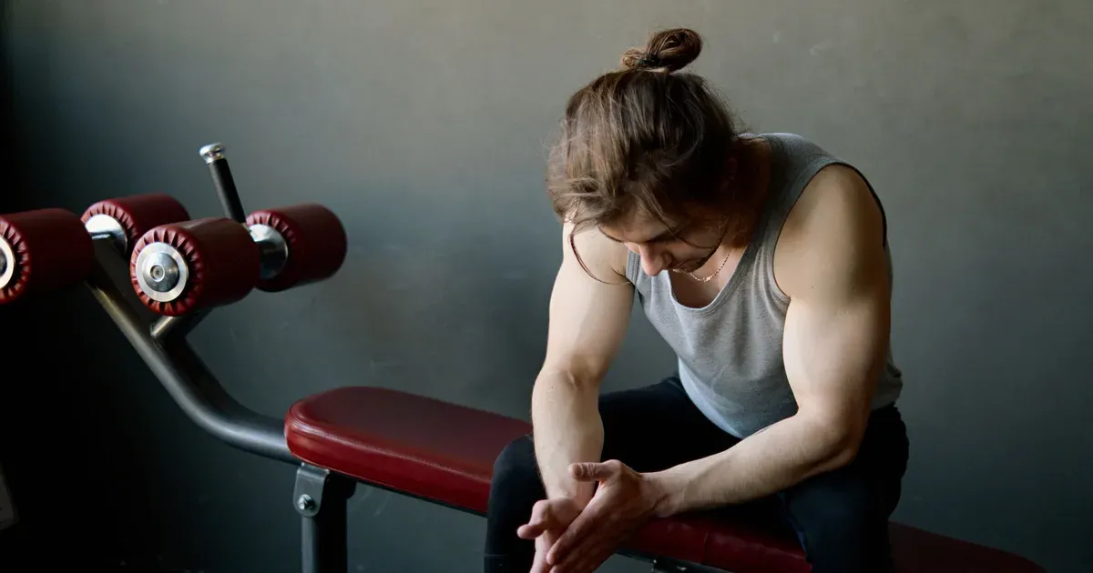 Pratiquant assis sur un banc de musculation, en récupération entre deux séries